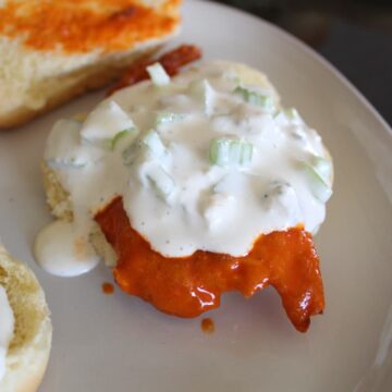 zoomed in shot of buffalo chicken slider with blue cheese dressing on a plate.