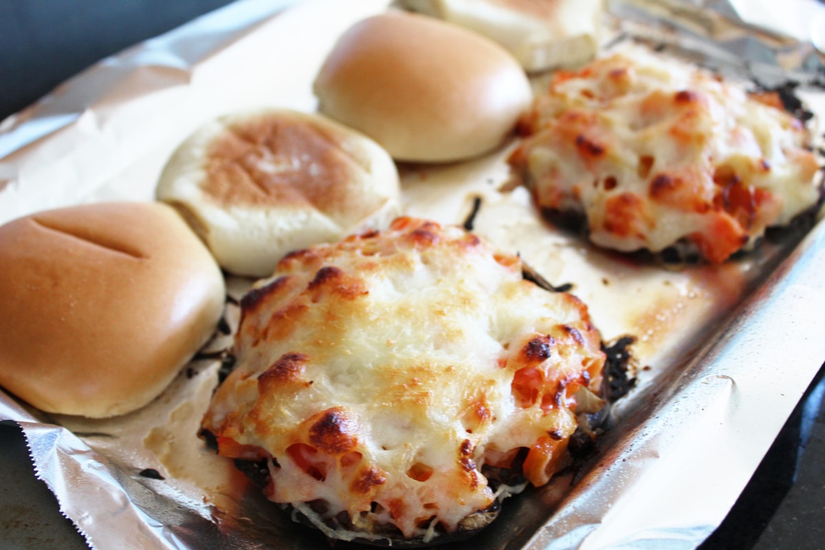 Stuffed Portobello mushrooms on a cooking sheet with cheese on top.