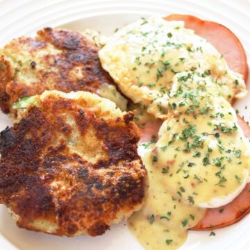 overhead shot of a plate of bubble and squeak with ham eggs and hollandaise sauce over the top.
