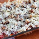 Chicken Parmesan in a baking dish baked and ready to eat. a cloth napkin next to it.