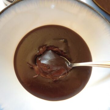 overhead shot of chocolate mousse in a bowl with a spoon in it.