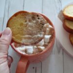 overhead shot of toast dipped into hot cocoa with marshmallows.