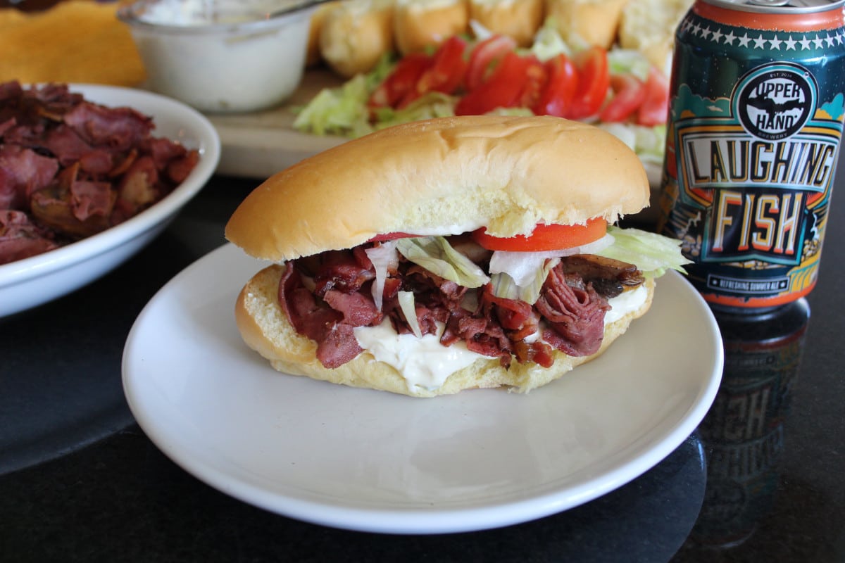 a beef sandwich on a plate with a craft beer pairing next to it.