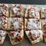 overhead shot of lasagna French bread pizza on a baking sheet.