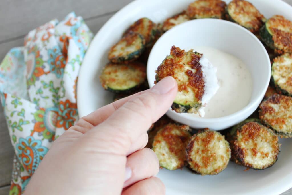 close up of a piece of fried zucchini with ranch on it