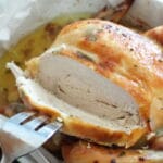 shot of a whole chicken carved with a piece being removed with a fork.