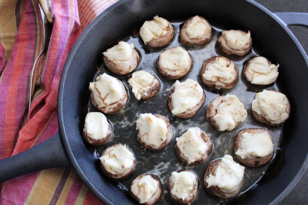 overhead shot of baked mushrooms in a cast iron pan with a cloth napkin next to it