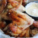 overhead shot of marinated baked chicken wings with dipping sauce in a pan.