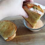 hand dipping chicken sandwich melt dipped into dressing.