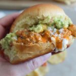 hand holding a ground turkey buffalo sloppy joe with avocado salad and blue cheese dressing.