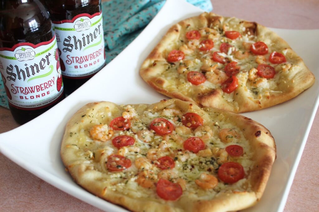 plate of scampi topped naan pizza with a craft beer pairing on the side.